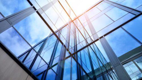 Modern office building with glass facade on a clear sky background. Transparent glass wall of office building.